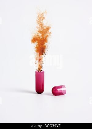 Open medicine capsule releasing a cloud of brown powder into the air with an explosion of healing molecules against a clean white background. Stock Photo