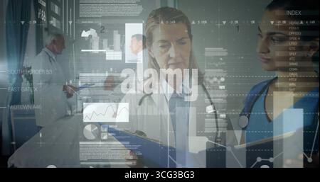 Examining senior doctor in white coat reading clipboard in hospital corridor, with holographic data Stock Photo
