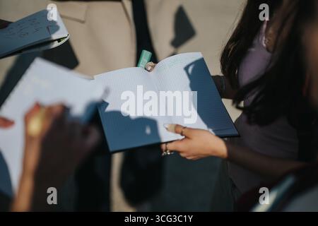 Students engaging in outdoor learning with professor and open notebooks Stock Photo