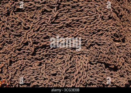This image displays a dense pile of rusted metal chains, emphasizing industrial decay and the texture of corroded iron links Stock Photo