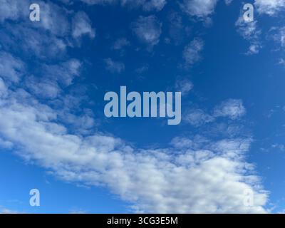 The bright blue sky is filled with fluffy white clouds, creating a beautiful cloudscape. Stock Photo