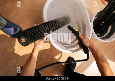 Top view of unrecognizable cleaning service employee washing air conditioner filter with steam cleaner, focusing on maintenance and cleaning tasks Stock Photo