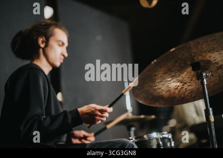 Young drummer performing passionately during a musical session in a studio Stock Photo