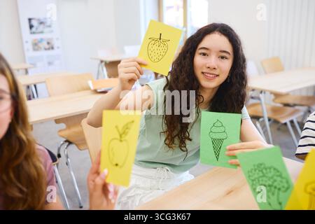 Students participate in an engaging educational activity using illustrated flashcards. The classroom setting emphasizes collaborative learning and cre Stock Photo