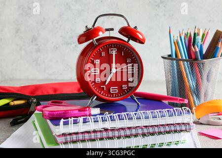 Alarm clock and notebooks on table against grey background Stock Photo