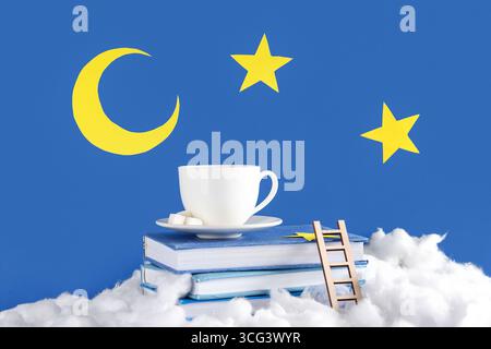Cotton clouds, books, cup of tea, paper moon and stars on blue background Stock Photo