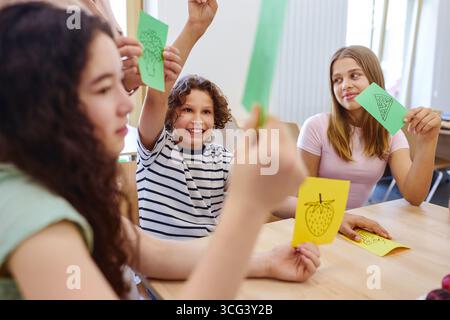 Group of schoolchildren engaging in an interactive classroom activity focused on learning about food themes. Bright and cooperative environment emphas Stock Photo