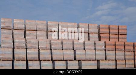Large stacks of red clay bricks on pallets at construction storage site Stock Photo