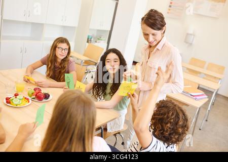 A teacher engages with a group of students in a classroom discussing healthy eating habits. Stock Photo