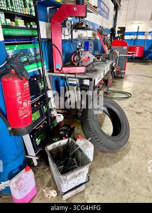 Busy automotive repair workshop with tire, fire extinguisher, and various tools and equipment. Stock Photo