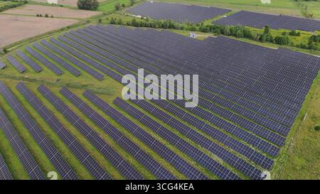 Aerial top down view of a massive solar panel farm installation on green field, representing renewable energy infrastructure, sustainability, and the Stock Photo