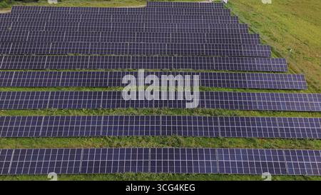 Aerial top down view of a massive solar panel farm installation on green field, representing renewable energy infrastructure, sustainability, and the Stock Photo