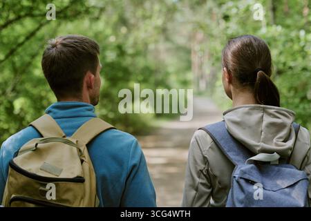 Young Man and Woman Walking Together Along Forest Trail Outdoors Stock Photo