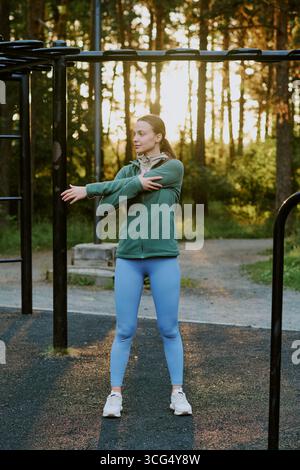 Young Adult Caucasian Woman Stretching Arms Outdoors during Morning Workout Stock Photo