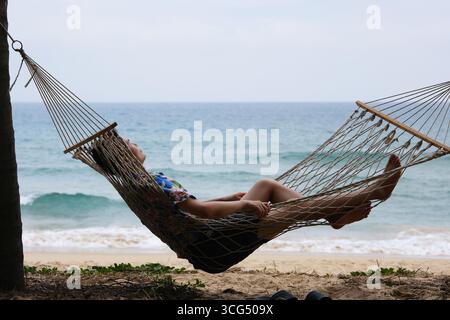 man relaxes in a hammock on the beach in Sanya, Hainan, China Stock Photo