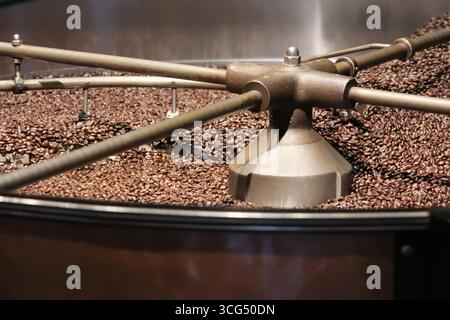 Close-up dark roasted coffee beans being stirred in a rotating cooling tray Stock Photo
