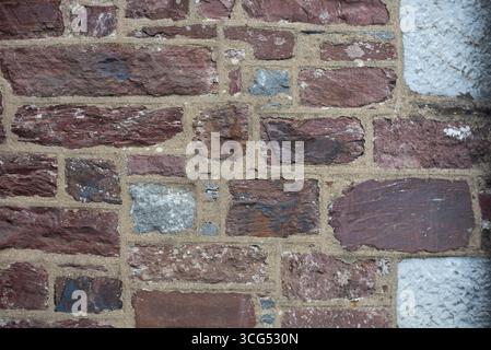 Close up of a rustic wall built from red bricks and occasional stone elements. The craftsmanship showcases a textured yet organized pattern, ideal for Stock Photo