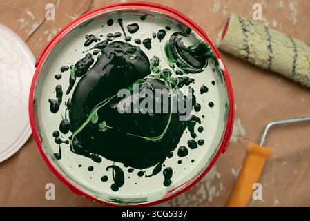 Green paint in a red bucket, ready for application with a roller, ideal for interior painting projects and renovation activities, captured in a detail Stock Photo