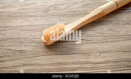 Close-Up of a Natural Bamboo Toothbrush on a Wooden Table Surface Stock Photo