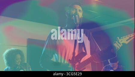 Performing bearded vocalist and guitarist strumming guitar singing on small stage, retro microphone Stock Photo