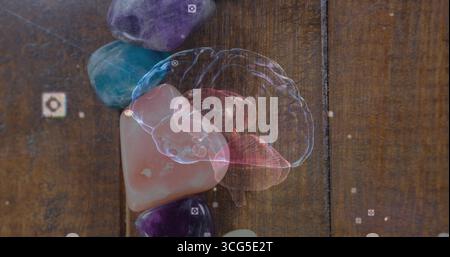 Displaying holographic brain model projecting over wooden tabletop, with gemstones and AR icons Stock Photo