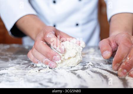 Bavaria, Germany - August 26, 2025: A baker kneads fresh dough with his hands on a floured work surface. Craftsmanship, tradition and passion combine in the art of baking to produce bread and pastries *** Ein Bäcker knetet mit den Händen frischen Teig auf einer bemehlten Arbeitsfläche. Handwerk, Tradition und Leidenschaft verbinden sich in der Backkunst zur Herstellung von Brot und Gebäck Stock Photo