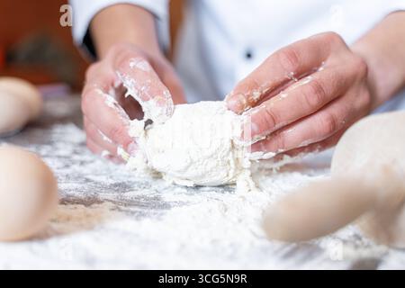 Bavaria, Germany - August 26, 2025: A baker kneads fresh dough with his hands on a floured work surface. Craftsmanship, tradition and passion combine in the art of baking to produce bread and pastries *** Ein Bäcker knetet mit den Händen frischen Teig auf einer bemehlten Arbeitsfläche. Handwerk, Tradition und Leidenschaft verbinden sich in der Backkunst zur Herstellung von Brot und Gebäck Stock Photo