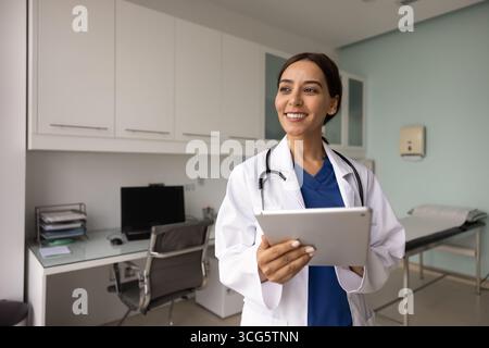 Happy young female Middle Eastern GP doctor holding digital tablet Stock Photo