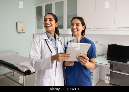 Two happy diverse female doctor colleagues using digital tablet Stock Photo
