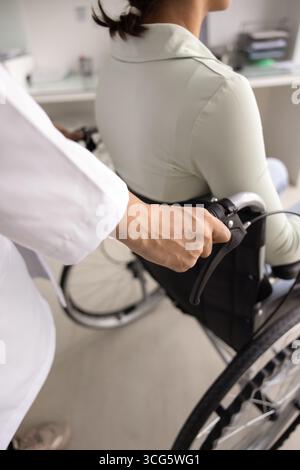 Cropped shot of doctor pushing wheelchair with female patient Stock Photo