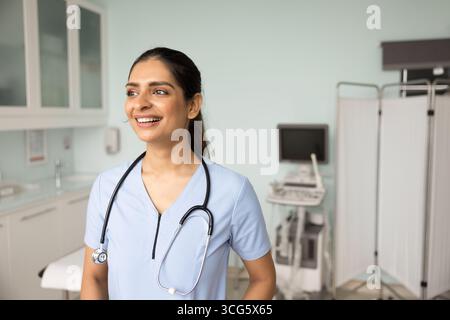 Happy young Indian doctor woman standing in ultrasound examination room Stock Photo