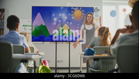Elementary School Students Studying Basic Information About Weather Factors in Modern Classroom. Female Teacher Explaining Water Cycles to Smart Kids During Geography Lesson Using Digital Screen. Stock Photo