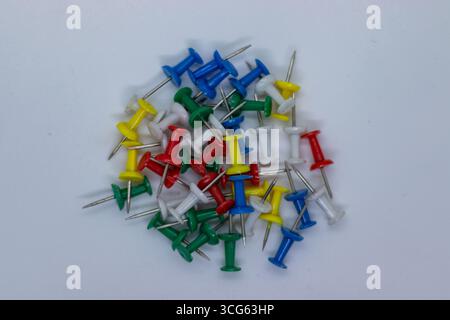 Close-up image of assorted colorful push pins with sharp metal points on a clean, minimal background. Ideal for office, school, organization. Stock Photo