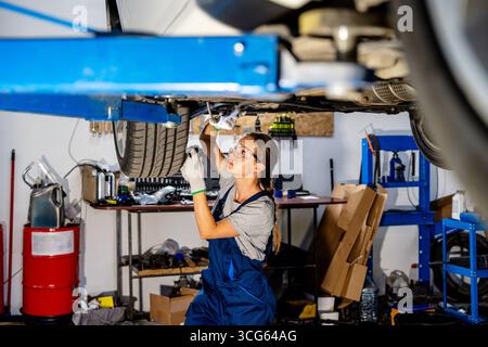 Woman mechanic repairing a car in auto repair shop Stock Photo