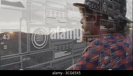 Standing man wearing safety helmet, plaid shirt analyzing AR data panels on hillside, copy space Stock Photo