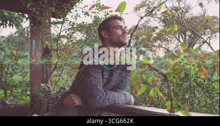 Leaning adult man gazing sideways on outdoor wooden porch railing, with audio waveform overlay Stock Photo