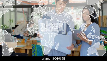 Reviewing blueprint and tablet, man and woman colleagues in shirt and dress collaborating in office Stock Photo
