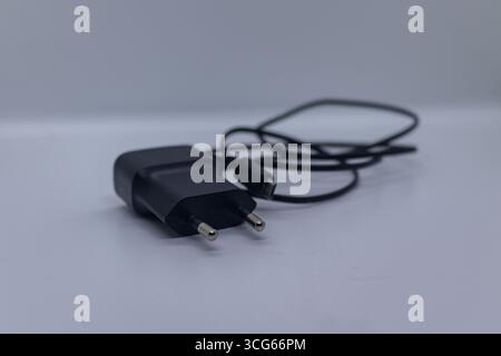 Compact black charger with USB cable designed for fast charging smartphones, tablets, and other devices. Portable and efficient power adapter ideal fo Stock Photo