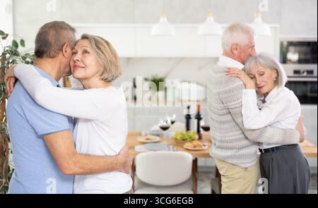 Two married couples enjoying slow dancing at house party for friends Stock Photo