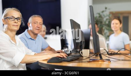 Old woman learning computer programs in training room Stock Photo