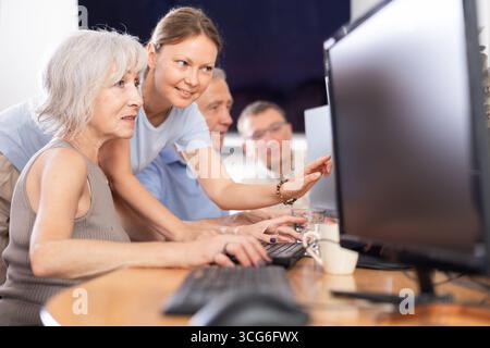 Young female mentor explaining something to elderly woman at computer lesson Stock Photo