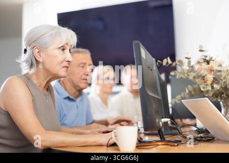 Old woman learning computer programs in training room Stock Photo