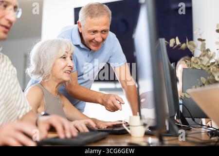 Senior woman attending computer class under guidance of aged teacher Stock Photo