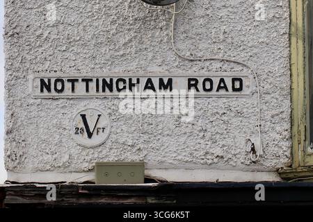 Vintage Nottingham Road street sign on roughcast building wall with historic cast iron water level marker, England, United Kingdom Stock Photo