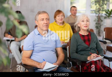 Group of older students sitting and listening at lesson Stock Photo