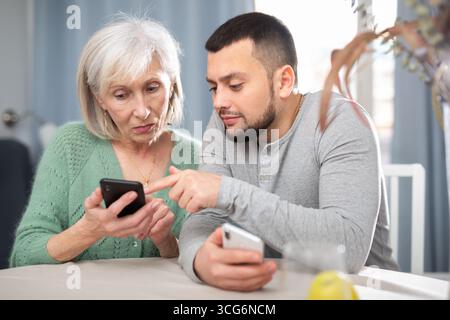 Man teaching his aged mother to use smartphone Stock Photo