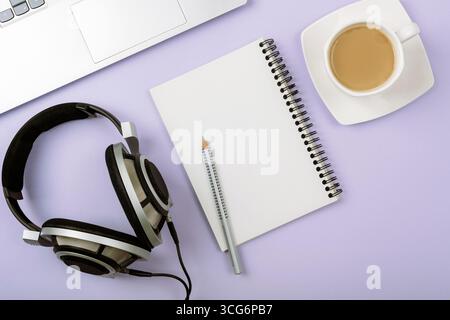 Top view of workspace with headphones, notebook, pencil, laptop and cup of coffee on pastel background. Top view, flat lay, mockup. Stock Photo