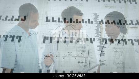 Doctors in lab coats discussing patient metrics in hospital, with pen, stethoscope and glass charts Stock Photo