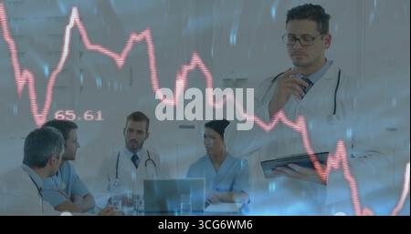 Doctor in white coat using tablet reviewing graph overlay on laptop in meeting room, copy space Stock Photo