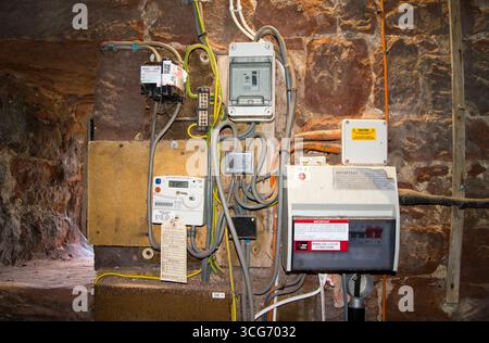 An electrical installation, including a meter, fusebox and residual current device (RCD), in a church tower in Cumbria, UK. The units are mounted on a sandstone wall adjacent to a window at left. Stock Photo